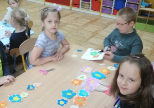 Dzieci ukladają wycięte kwiaty na stoliku